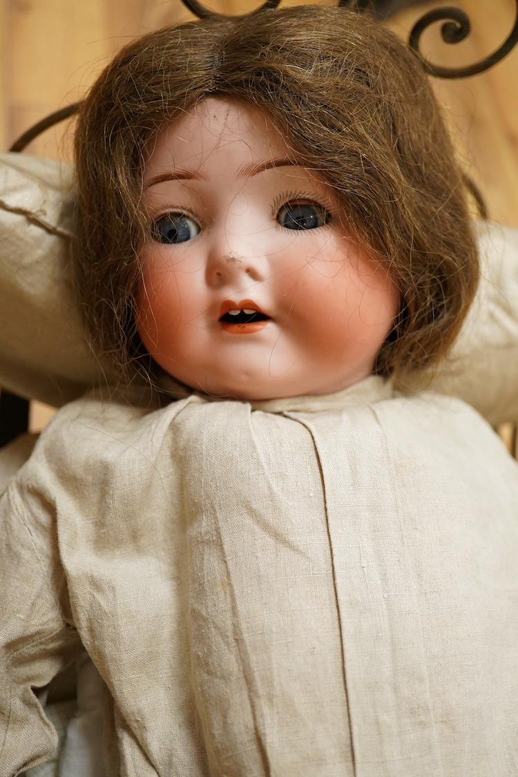 An Heubach Koppelsdorf bisque doll, mould 320 with sleeping eyes, open mouth and jointed composition body, together with a tubular and wrought metal half-tester bed, on casters, related clothing and bedding, doll 64cm